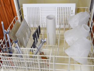 A dishwasher in an apartment with a basket full of cleaning supplies in the SW Houston Westchase Area.