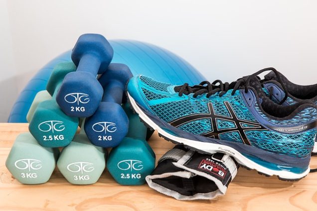 A pair of Asics shoes and a pair of dumbbells on a wooden table in an apartment in Westpark.