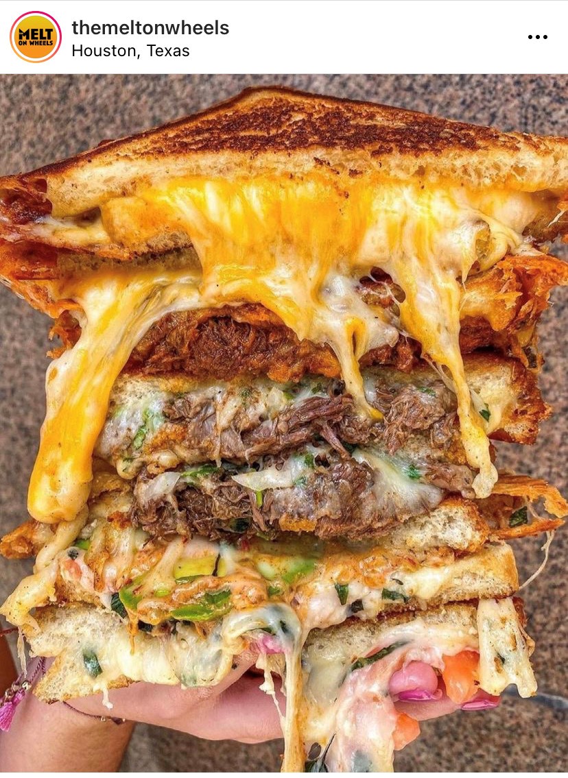 A person is holding up a mouthwatering grilled cheese sandwich.